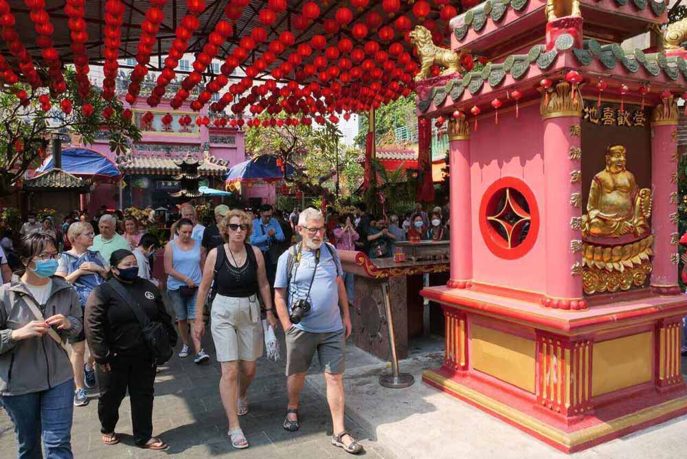 Travelers observing respectful etiquette inside a sacred place in Hoi An