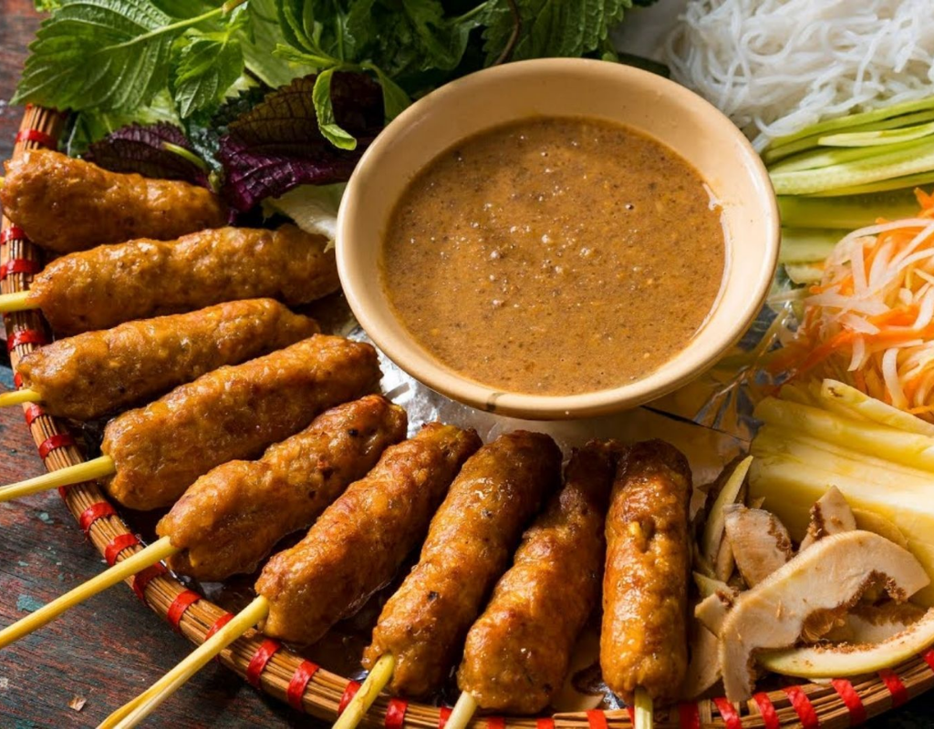 Smoky grilled meat served with herbs, rice paper, and dipping sauce creates a flavorful hands-on dining experience.