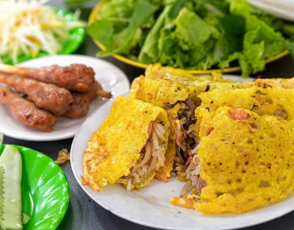 Crispy Banh Xeo is wrapped with fresh herbs and rice paper before being dipped into a flavorful sauce.