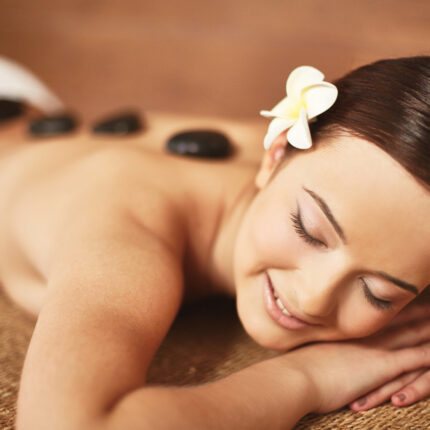 Portrait of young girl enjoying hot stone procedure in beauty salon